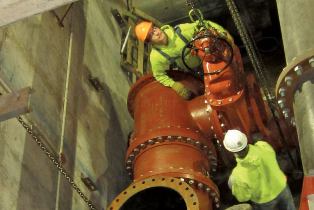 2 workers installing pipes in pit