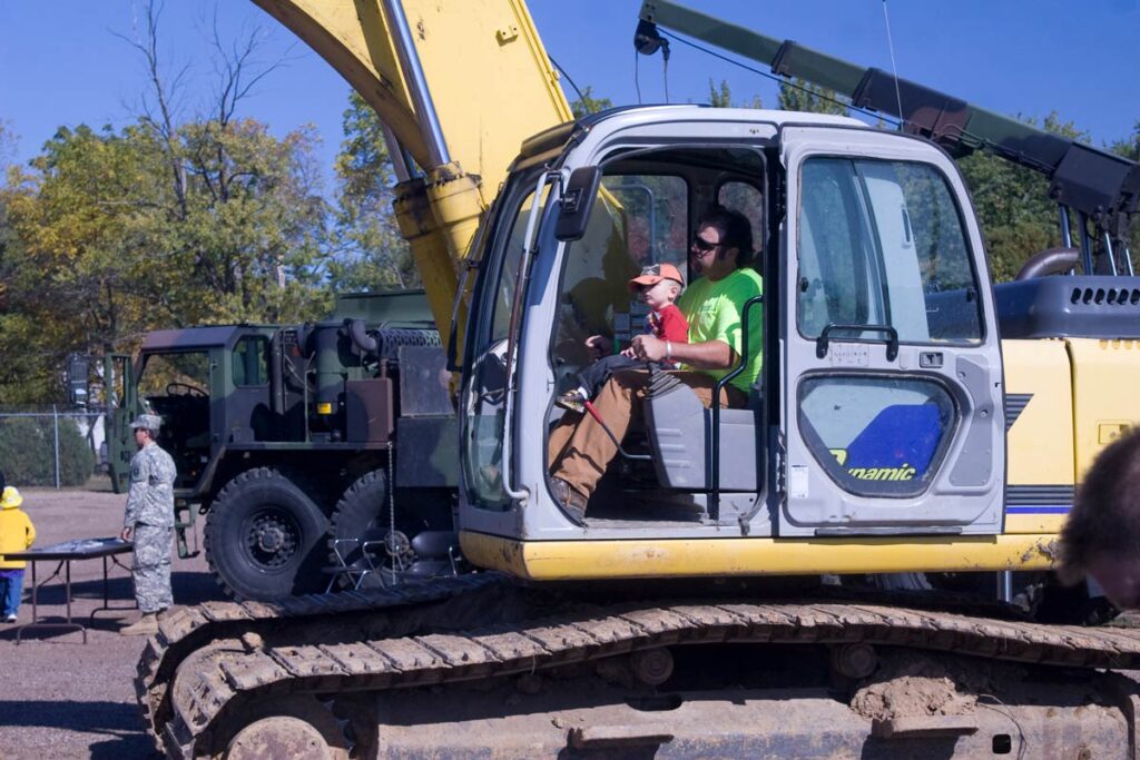 a Staab employee sitting in an excavator with a little boy