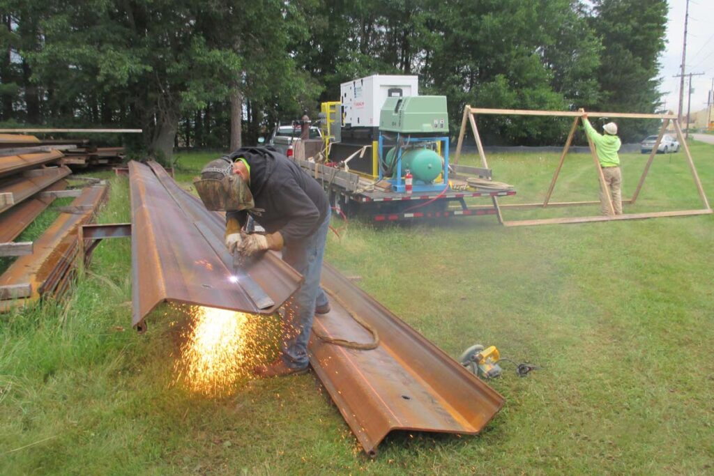 Staabco employee using a laser cutter on a metal beam