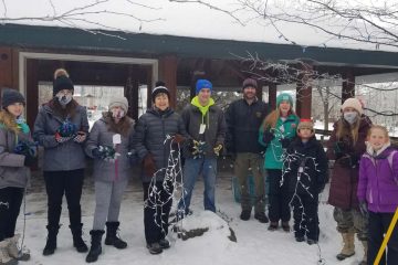 people in masks holding Christmas lights in the snow